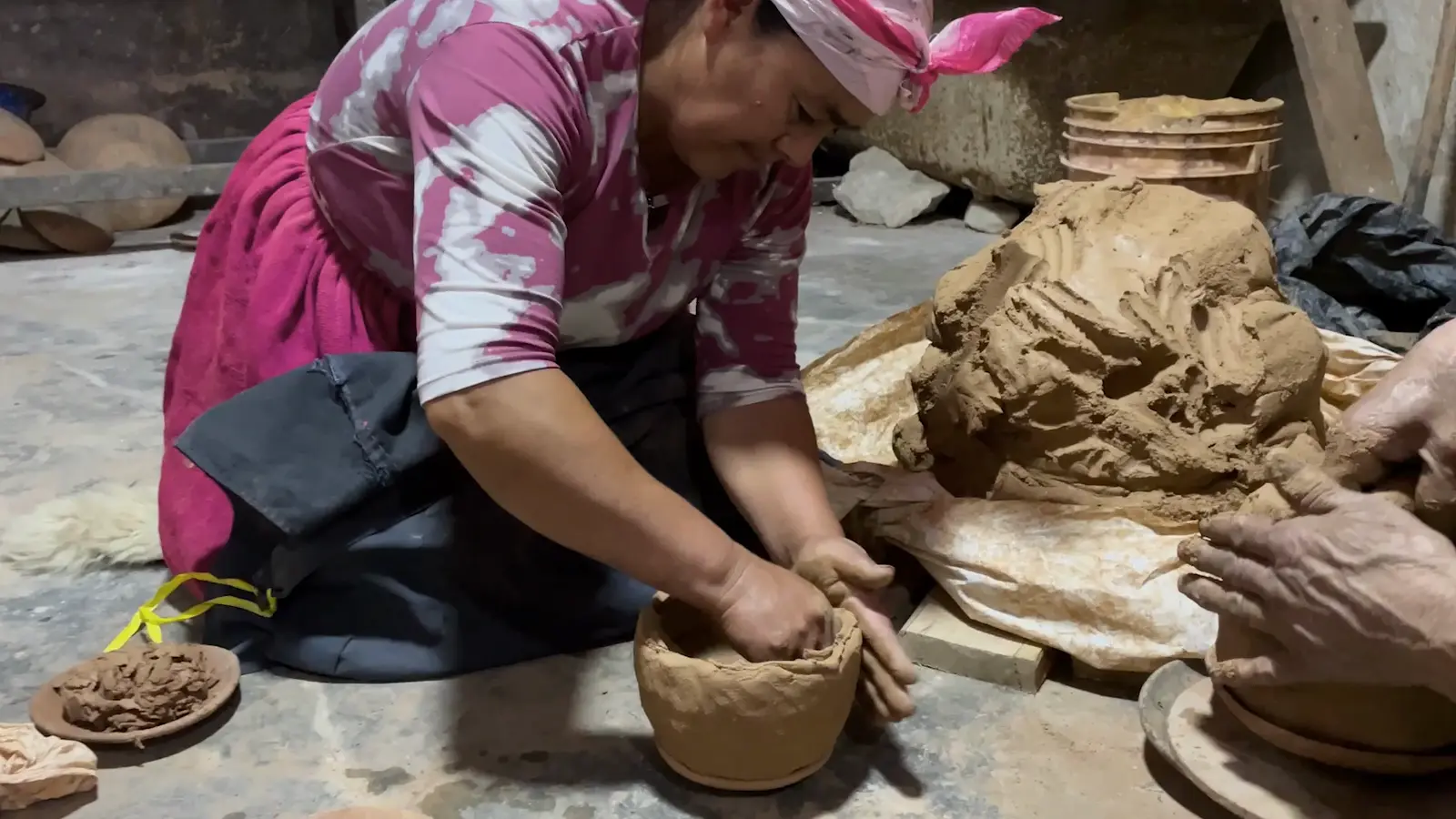 Manos de una alfarera de La Cusana modelando una vasija de barro.