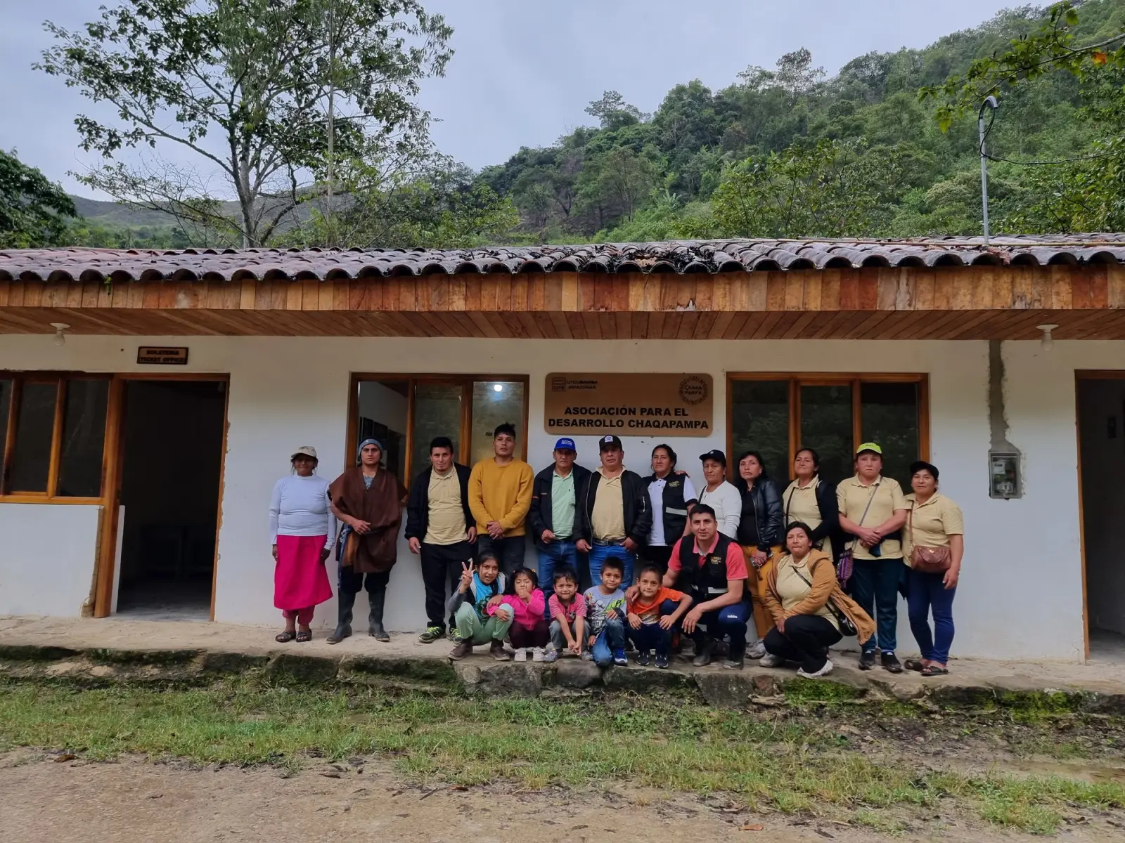 Grupo de adultos y niños frente al local de la Asociación para el Desarrollo Chaqapampa