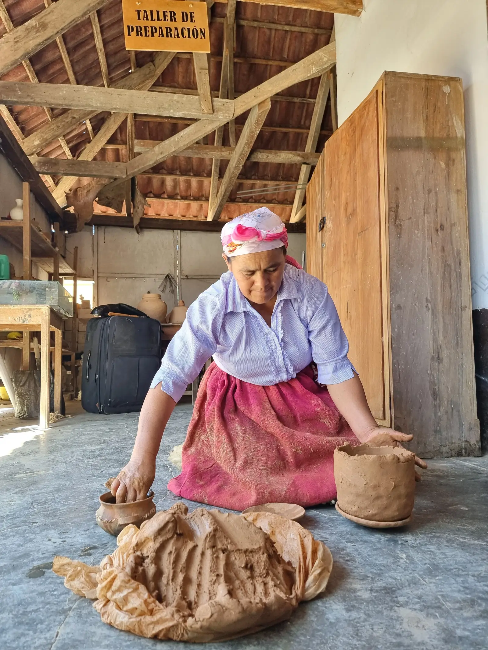 Artesana modelando a mano una vasija de arcilla en el taller de preparación