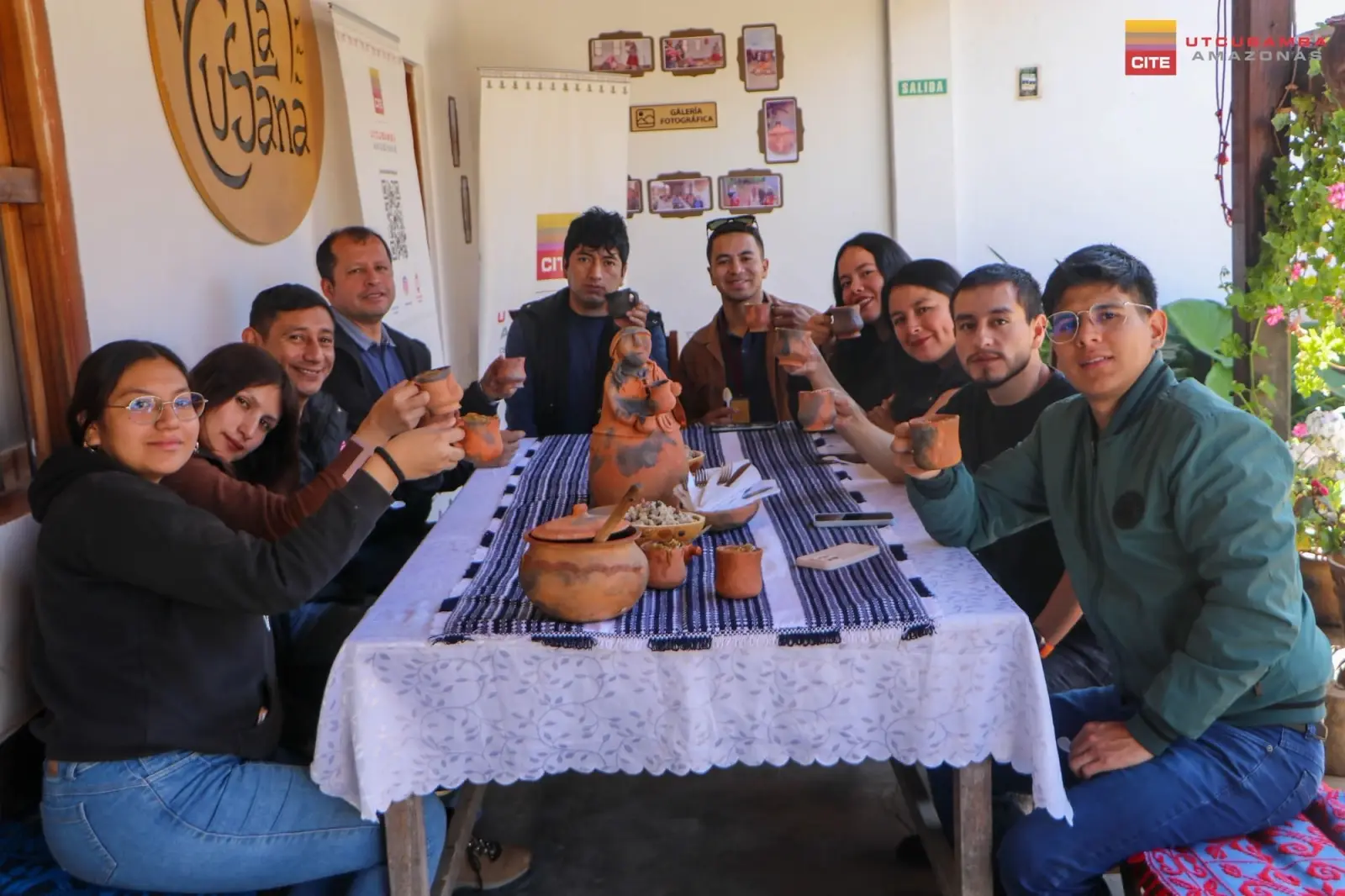 Visitantes brindan con tazas de cerámica alrededor de una mesa en el local de La Cusana