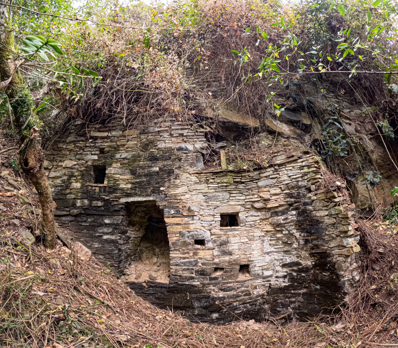 Recinto de piedra laja con ventanas pequeñas construido bajo un alero rocoso