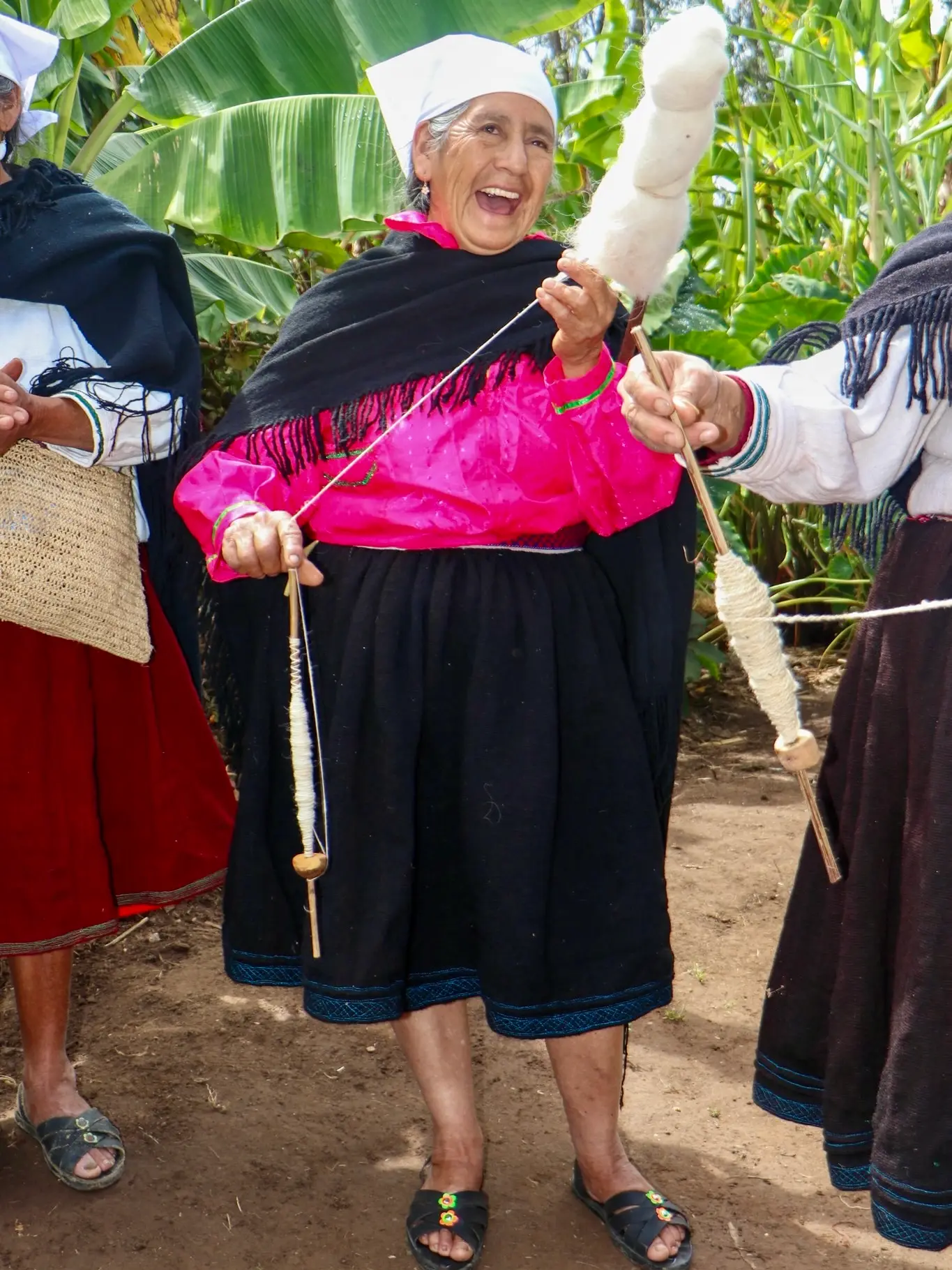 Artesana hilando lana de oveja con pushcana junto a otras hilanderas