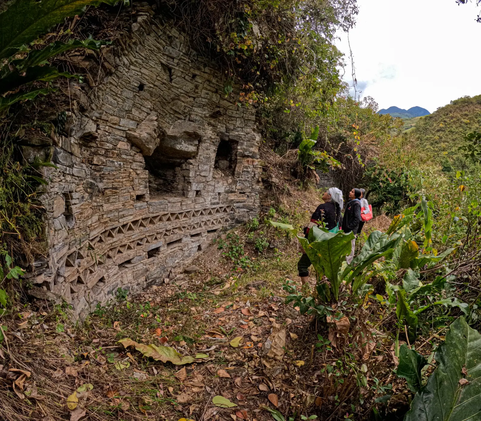 Visitantes recorren el Sitio Arqueológico Sholón junto a un muro con frisos geométricos