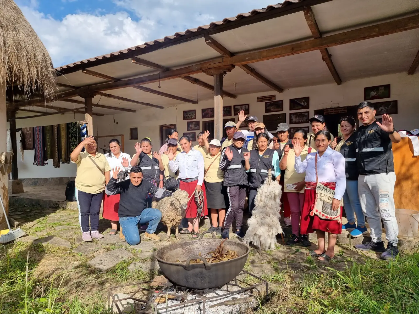 Artesanas y visitantes saludando en el patio del taller junto a una paila al fuego