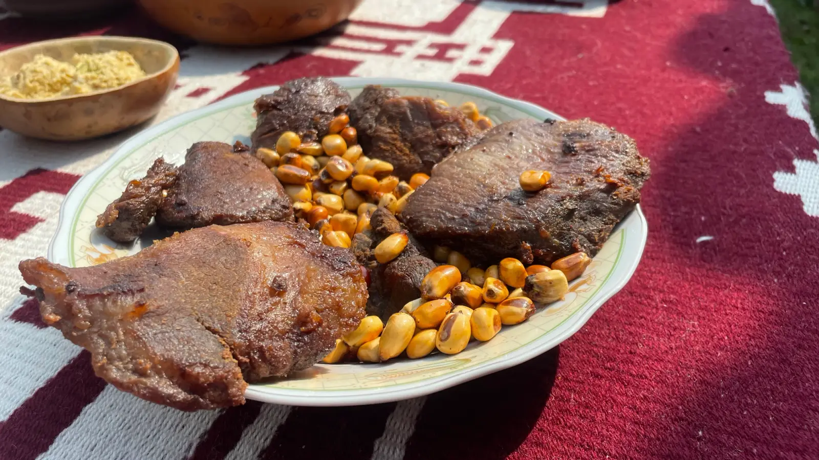 Plato de cecina con cancha servido sobre una manta tejida roja