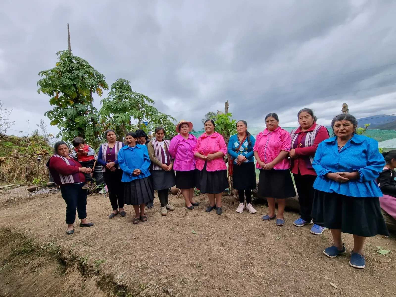 Grupo de artesanas con blusas fucsia y azules reunidas al aire libre