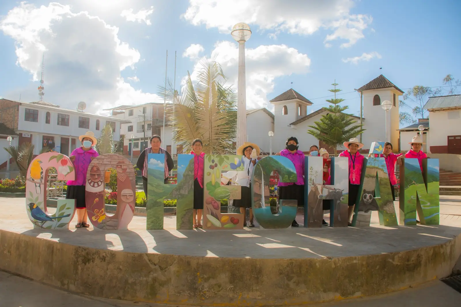 Artesanas detrás de las letras pintadas de Cohechán en la plaza del pueblo